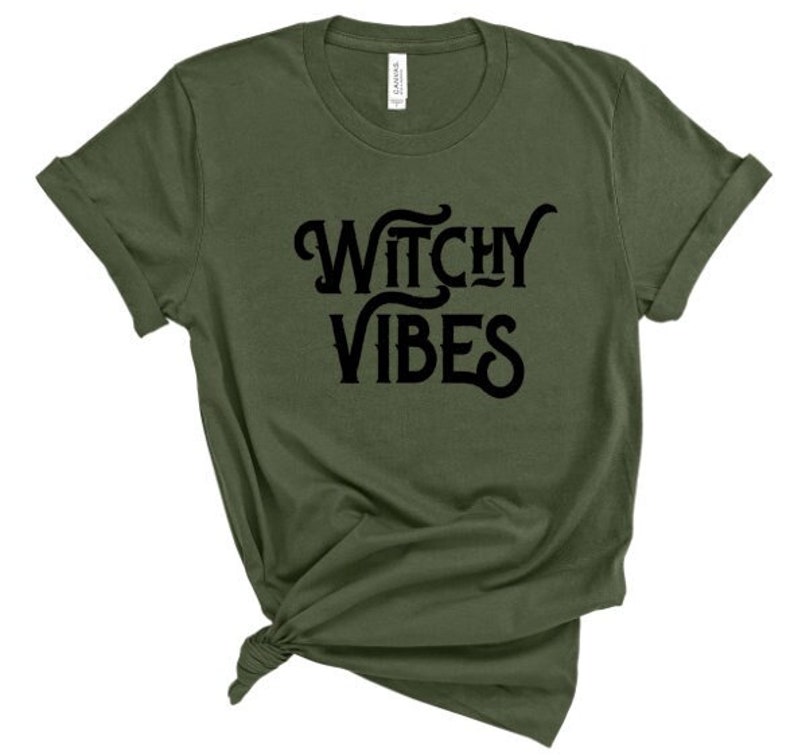 K&ouml;nnte beinhalten: Ein gr&uuml;nes T-Shirt mit dem Text "Witchy Vibes" in schwarzen Buchstaben.