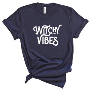 K&ouml;nnte beinhalten: Ein marineblaues T-Shirt mit dem Text "Witchy Vibes" in wei&szlig;en Buchstaben.