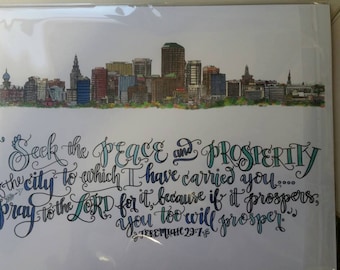 Puede incluir: Una tarjeta blanca con una ilustración de ciudad en azul y verde y una cita manuscrita de Jeremías 29:7. La cita dice "Busquen la paz y la prosperidad de la ciudad a la que los he llevado... oren al Señor por ella, porque si ella prospera, ustedes también prosperarán."