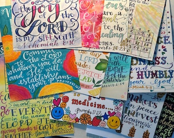 Puede incluir: Una colección de láminas artísticas con caligrafía hecha a mano, letras coloridas e ilustraciones de flores, frutas y caras sonrientes. Las láminas muestran varios versículos religiosos y citas, incluyendo Nehemías 8:10, Proverbios 16:24, Proverbios 16:3, Habacuc 2:14, Miqueas 6:8, Proverbios 17:22, Colosenses 3:17 y Santiago 3:18.