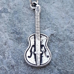 May include: A silver charm in the shape of a guitar. The charm has a detailed design and a loop at the top for attaching to a bracelet or necklace.