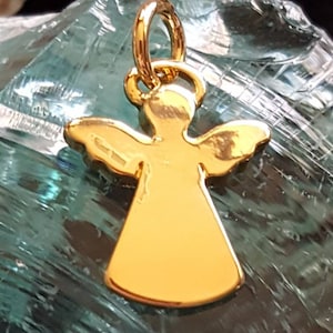 May include: A gold angel charm pendant with a halo and wings. The charm is on a green background.