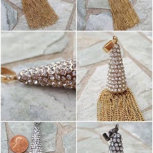 May include: A gold-toned tassel pendant with a cone-shaped top encrusted with clear rhinestones. The tassel is made of numerous gold chains. A similar pendant is shown with a silver-toned tassel.