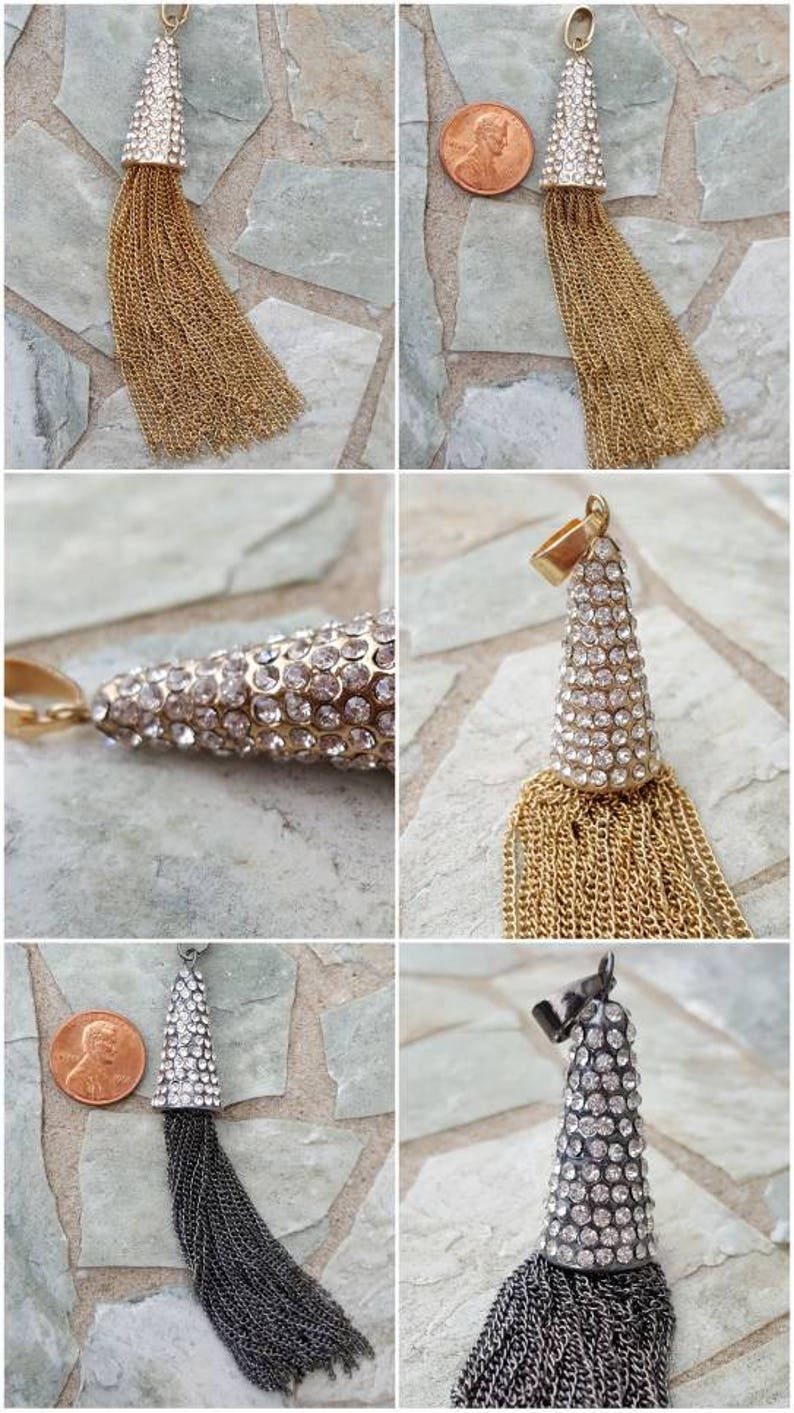 May include: A gold-toned tassel pendant with a cone-shaped top encrusted with clear rhinestones. The tassel is made of numerous gold chains. A similar pendant is shown with a silver-toned tassel.