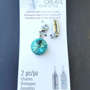 May include: A turquoise blue crystal charm with a silver clasp and a silver tag that says "December". The charm is packaged on a white card with the words "Create Your Style" and "Charms with Swarovski crystals".