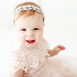 May include: A silver-toned headband featuring a dense arrangement of clear, sparkling crystals in a floral-inspired pattern. The accessory is worn across the forehead, showcasing a metallic base with intricate, reflective stone detailing throughout.