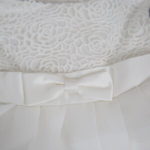 Puede incluir: Un vestido blanco sin mangas con un corpi&ntilde;o de encaje y un lazo de sat&eacute;n en la cintura.