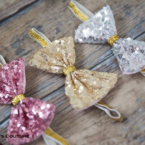 May include: Three sequined bow headbands in pink, gold, and silver with gold elastic bands.