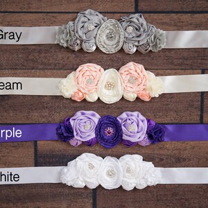 May include: Four satin sashes with different colored ribbons and flower embellishments. The sashes are labeled "Gray", "Cream", "Purple", and "White".