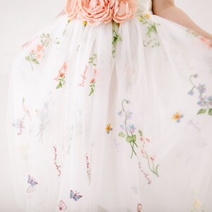 Puede incluir: Falda de tul blanca con bordado floral y las palabras "Birdhouse", "Sweet", "My Daisy", "Violet" y "Forget Me Not".