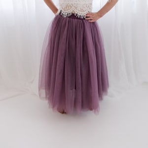 May include: A long, flowing purple tulle skirt. The skirt is gathered at the waist and falls to the ankles.