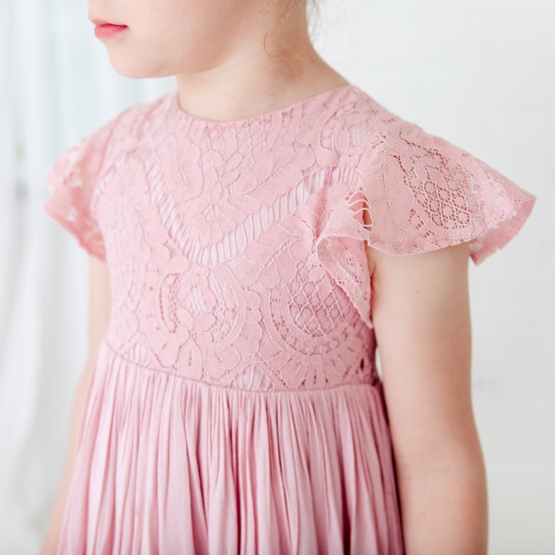 May include: A pink lace dress with short, ruffled sleeves and a pleated skirt.