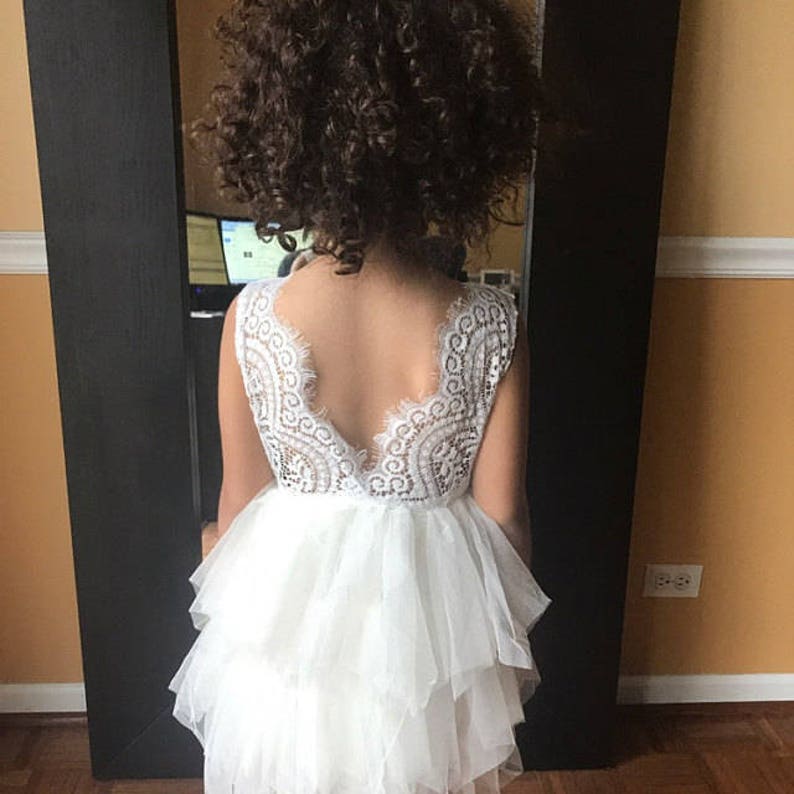 May include: White tulle dress with a lace bodice and a deep V-back. The dress has multiple layers of tulle and is perfect for a special occasion.