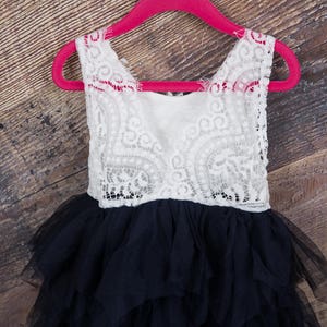 Puede incluir: Un vestido de tul de capas negras y blancas con un corpi&ntilde;o de encaje blanco. El vestido est&aacute; colgado en una percha rosa.