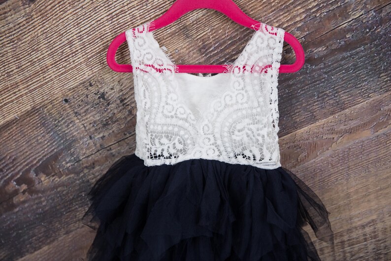 Puede incluir: Un vestido de tul de capas negras y blancas con un corpi&ntilde;o de encaje blanco. El vestido est&aacute; colgado en una percha rosa.