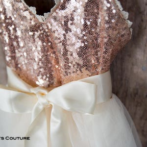 May include: A rose gold sequined bodice with a white tulle skirt and a white satin bow.