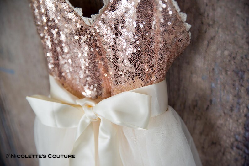May include: A rose gold sequined bodice with a white tulle skirt and a white satin bow.