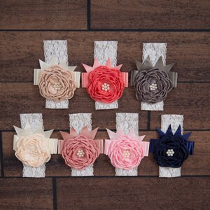 May include: Seven white lace headbands with different colored fabric flowers. The flowers are peach, coral, pink, gray, and navy blue. Each flower has a pearl in the center.