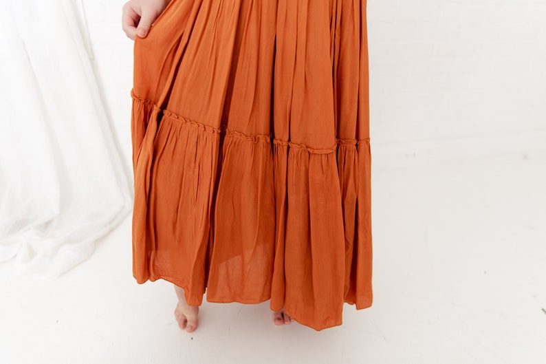 Op de afbeelding: Een lange, roestkleurige gelaagde rok met een gerimpelde zoom.