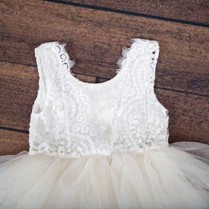 May include: A white tulle dress with a lace bodice. The dress has a sleeveless design and a full skirt.