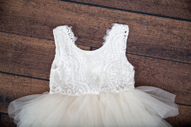 May include: A white tulle dress with a lace bodice. The dress has a sleeveless design and a full skirt.