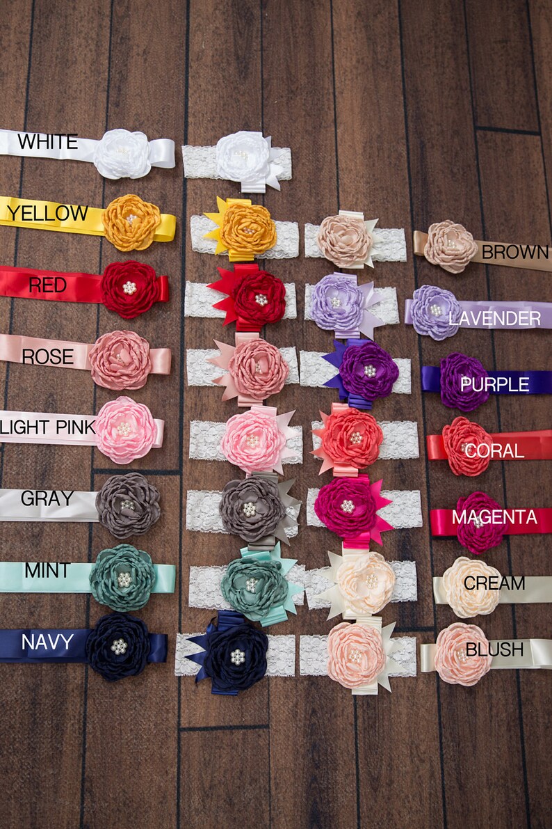 May include: A set of 16 flower headbands in various colors, including white, yellow, red, rose, light pink, gray, mint, navy, brown, lavender, purple, coral, magenta, cream, and blush. Each headband features a double flower with a lace trim.