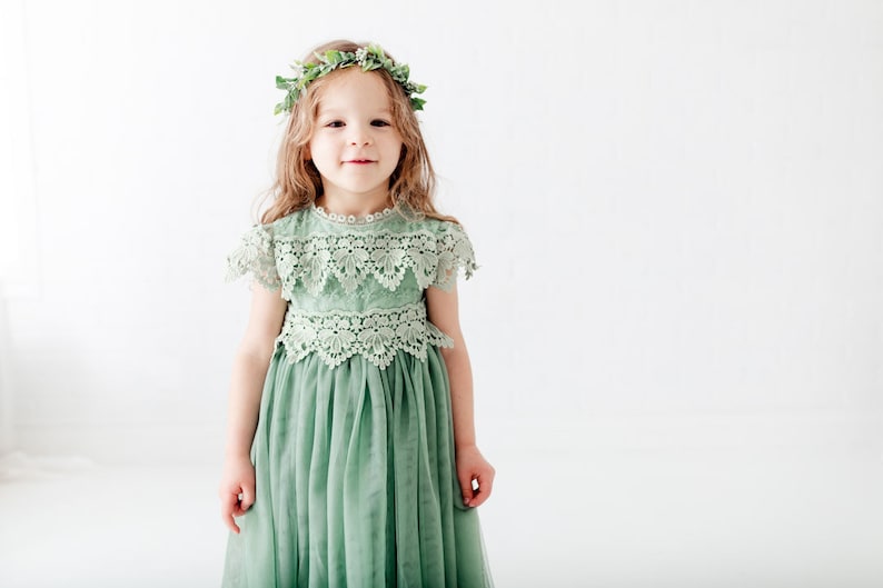 May include: A young girl wearing a sage green tulle dress with lace detailing and a green leaf crown.