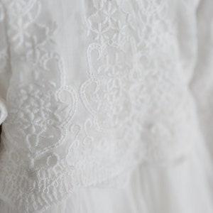 May include: White lace fabric with a delicate floral pattern. The lace is soft and flowing, and the pattern is intricate and beautiful.