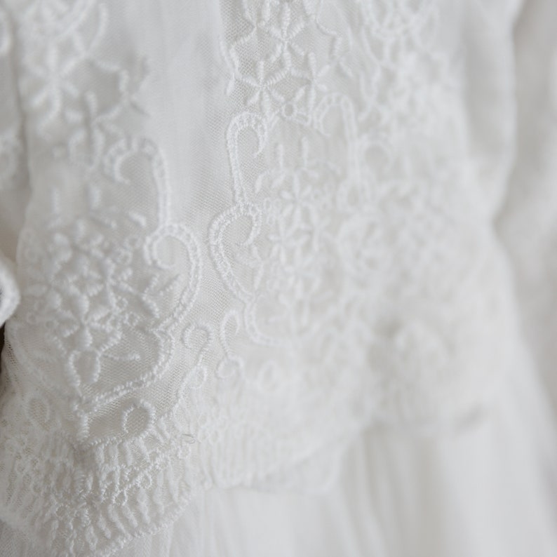 May include: White lace fabric with a delicate floral pattern. The lace is soft and flowing, and the pattern is intricate and beautiful.