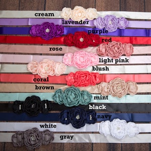May include: A set of 14 satin ribbon sashes with matching flower embellishments in various colors, including cream, lavender, rose, purple, red, light pink, blush, coral, brown, mint, black, navy, white, and gray.