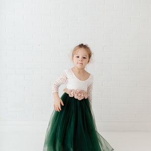Pu&ograve; includere: Un abito lungo fino ai piedi con corpetto in pizzo bianco a maniche a tre quarti e gonna in tulle verde scuro. Una larga fascia color marrone chiaro &egrave; annodata in vita, decorata con tre grandi fiori in tessuto abbinati al centro.