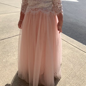 May include: A pale pink tulle skirt with a white lace top. The skirt is long and flowing, and the top has a delicate lace pattern.