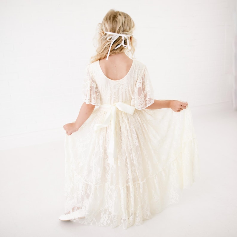 以下が含まれることがあります： 白いレースのドレスにサテンのリボンと白いヘッドバンドが付いている。ドレスはゆったりとしたスカートで、特別な機会に最適です。