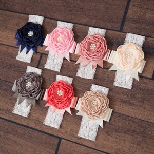 Puede incluir: Surtido de ocho diademas de encaje blanco con flores de tela de diferentes colores. Las flores est&aacute;n hechas de sat&eacute;n y tienen un centro de perla. Los colores de las flores son azul marino, rosa, coral, melocot&oacute;n y gris.