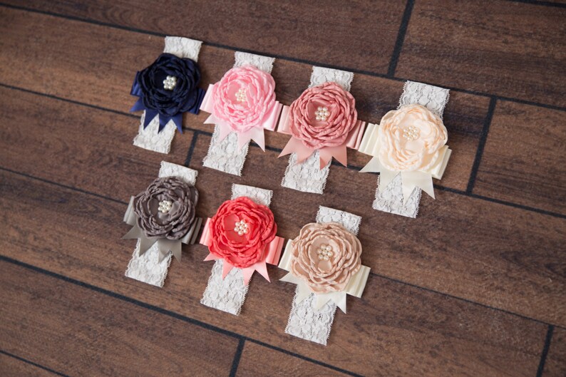Puede incluir: Surtido de ocho diademas de encaje blanco con flores de tela de diferentes colores. Las flores est&aacute;n hechas de sat&eacute;n y tienen un centro de perla. Los colores de las flores son azul marino, rosa, coral, melocot&oacute;n y gris.