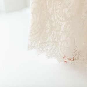 May include: A white lace fabric with a delicate floral pattern. The fabric is soft and flowing, and it would be perfect for a wedding dress or other special occasion.