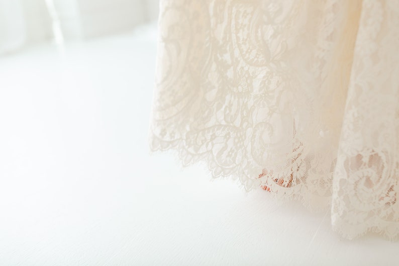May include: A white lace fabric with a delicate floral pattern. The fabric is soft and flowing, and it would be perfect for a wedding dress or other special occasion.
