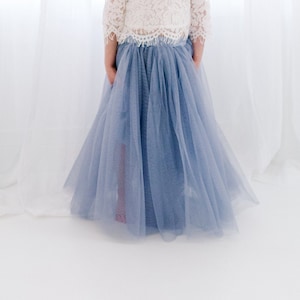 May include: A light blue tulle skirt with a white lace top. The skirt is full and flowing, and the top is delicate and feminine.