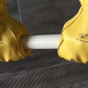 May include: A pair of yellow leather work gloves with the text "BURNS INSURANCE" printed on the back of each glove. The gloves are held up by a white pipe.