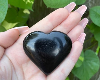 May include: A black obsidian heart-shaped crystal. The crystal is smooth and polished, with a high gloss finish.