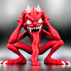 May include: A red figurine of a crouching creature with two white horns, large white eyes, and a wide, toothy grin. A long, red tongue extends from its mouth, reaching down toward the base. The creature has its hands placed on its head.
