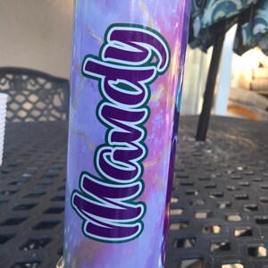 May include: A purple and gold marble patterned tumbler with the name "Mandy" written in purple and green letters.