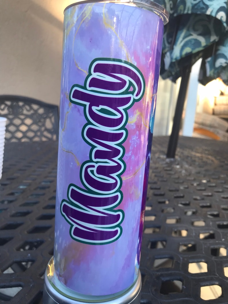 May include: A purple and gold marble patterned tumbler with the name "Mandy" written in purple and green letters.