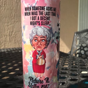 May include: A pink and white tumbler with a cartoon image of a woman with a quote that reads "WHEN SOMEONE ASHS ME WHEN WAS THE LAST TIME I GOT A DECENT NIGHT'S SLEEP... Picture H. Sicily, 1912".