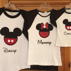 May include: Three white t-shirts with black sleeves, featuring a Mickey Mouse design and the words "Daddy", "Mommy", and "Camden".