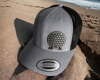 May include: Gray and black baseball cap with a black mesh back. The cap features a silver embroidered logo of the Spaceship Earth attraction at Epcot.