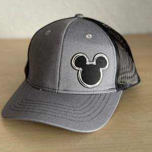May include: A gray and black trucker hat with a black Mickey Mouse silhouette on the front.