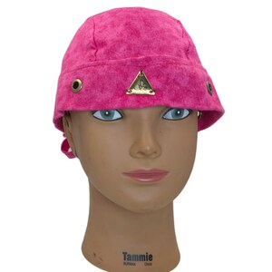 May include: A vibrant pink bucket hat with a textured fabric. The hat features a small gold-colored triangle emblem and brass eyelets. The hat is displayed on a mannequin head.