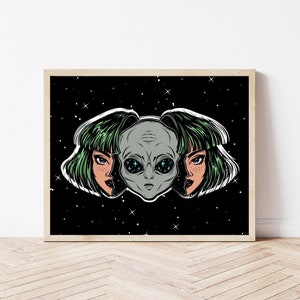May include: A framed art print featuring a stylized illustration of an alien head flanked by two human faces. The alien has large eyes and the faces have green hair. The background is black with white stars.