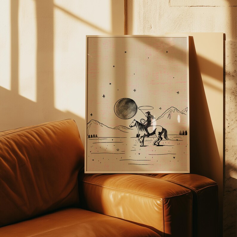 Puede incluir: Una impresi&oacute;n art&iacute;stica enmarcada que presenta a un vaquero montado a caballo bajo una gran luna. La ilustraci&oacute;n en blanco y negro representa un paisaje des&eacute;rtico con monta&ntilde;as y estrellas. La obra de arte tiene una est&eacute;tica vintage y r&uacute;stica.